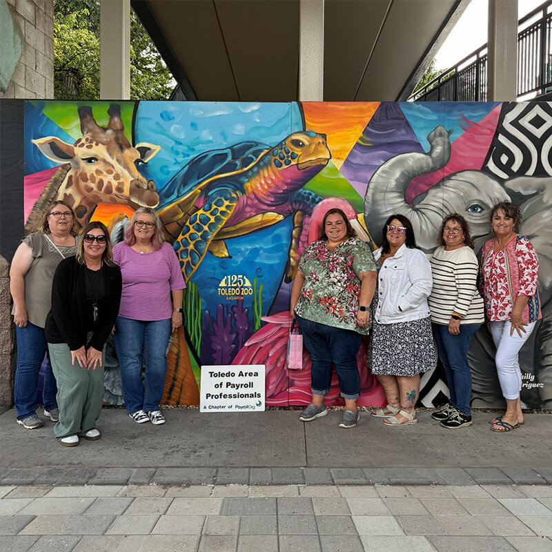 Group of women posing in front of mural art